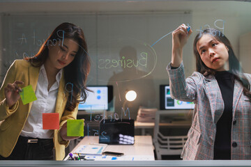 Businesswomen planning project strategy on glass board