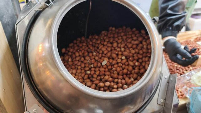 Metal roasters handle Asian market snacks preparation. Efficient Asian market snacks production ensures fast supply. Freshly roasted peanuts, classic Asian market snacks, ready for sale.