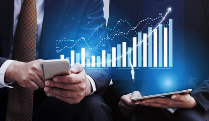 Two business professionals engage in data analysis using a smartphone and tablet, highlighting trends and growth within a modern office environment. Impute