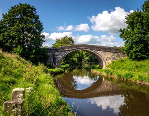 Stone arched bridge over a calm river with bright summer foliage