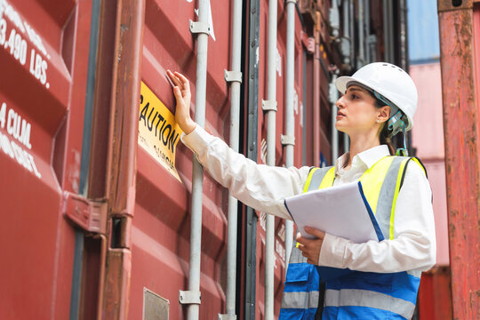 Female Engineer Inspecting Cargo Container with Caution Sign at Port Terminal, Woman Worker Examining and Checking Inventory Documentation Shipping Box Exterior