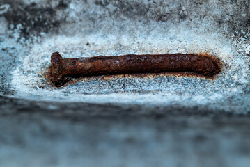A rusty nail lay on the rough textured concrete surface.