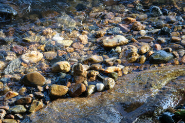 Small stone cairn balanced in clear flowing stream over wet pebbles. natural riverbed creates serene, tranquil background, evoking feeling of peace and harmony