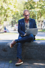 Obraz premium Mature man working remote on laptop in park