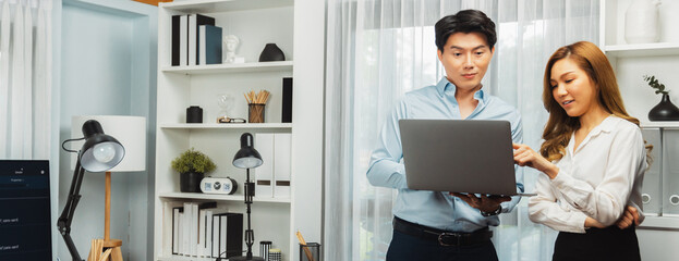 Panoramic image of smiling IT developers standing with laptop at corner modern office, talking online software development information data of application and website intelligence system. Infobahn.