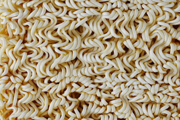 A high-angle, full-frame macro shot of dry, uncooked instant noodles, showcasing their intricate, wavy, and interconnected texture.