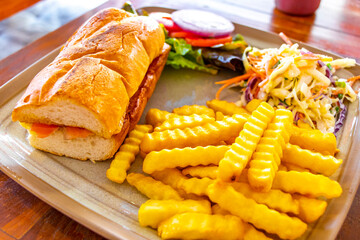 Salmon baguette sandwich with salad and French fries in Thailand.