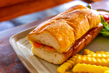 Salmon baguette sandwich with salad and French fries in Thailand.
