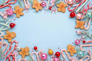 heerful and colorful Christmas, Holiday flat lay featuring gingerbread men and candy canes on a light blue background, surrounding a central blank area. copy space