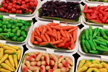 Appetizing colorful Thai dessert sweet food called Luk Chup. traditional Thai candy made from mung bean in fruit shape, vibrant display of Asian cuisine at market