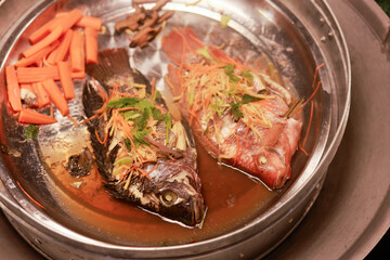 Delicious Asian steamed fish head with ginger, scallion and carrot. An appetizing and traditional Chinese seafood meal for healthy dinner, looking fresh and homemade