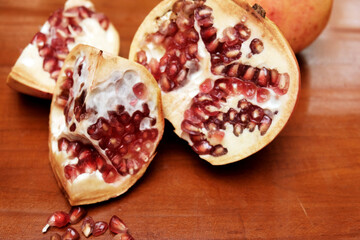 Freshly picked pomegranates sliced and ready to be eaten on a wooden table, Pomegranates are juicy, sweet fruits with edible seeds called arils packed tightly inside. 