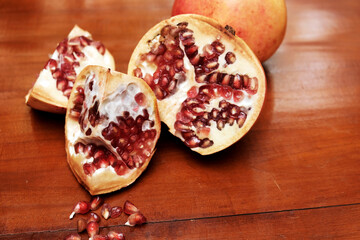 Freshly picked pomegranates sliced and ready to be eaten on a wooden table, Pomegranates are juicy, sweet fruits with edible seeds called arils packed tightly inside. 