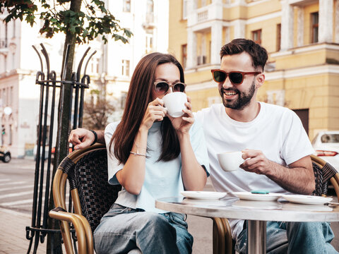 Smiling beautiful woman and her handsome boyfriend. Happy cheerful family. Couple drinking coffee&nbsp;in restaurant. They drinking tea at cafe in the street. Holding cup. Enjoying their date