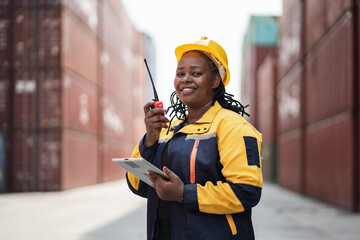 Portrait African woman logistics workers use notebook computer and walkie talkie checking container	