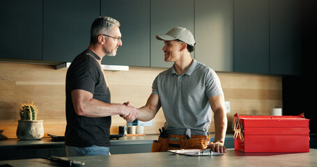 Men, plumber and client with handshake in kitchen for solution, maintenance and leak repair....