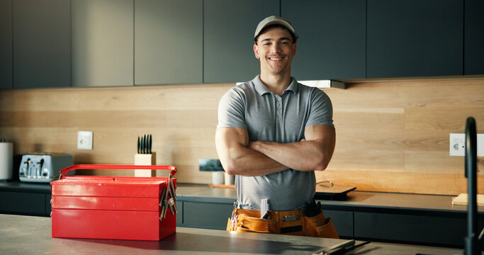 Portrait, plumber and happy man in kitchen with arms crossed for pride, confidence or tradesman. Smile, repair person and plumbing professional in home, maintenance handyman or pipe fitter in Spain