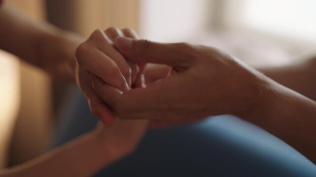 Close-up of loving hands gently caressing. Woman providing therapeutic and caring touch while massaging man palm and fingers symbolizing love and connection. Shooting in slow motion.
