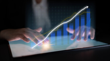 A business professional is using innovative technology to analyze digital data trends on a tablet, showcasing growth and strategic insights for informed decision-making. Impute