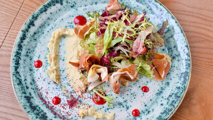 White salad with vegetables and hummus in a plate on the table macro photo