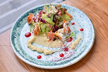 Green salad with vegetables and hummus in a plate on the table