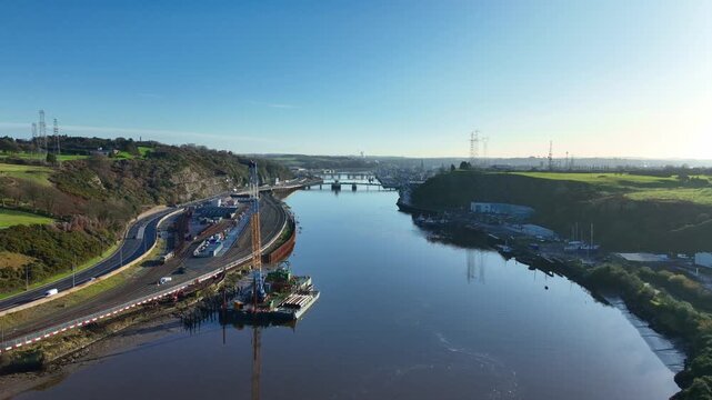 Waterford City drone flying to city over majestic River Suir with railway station and yards early morning