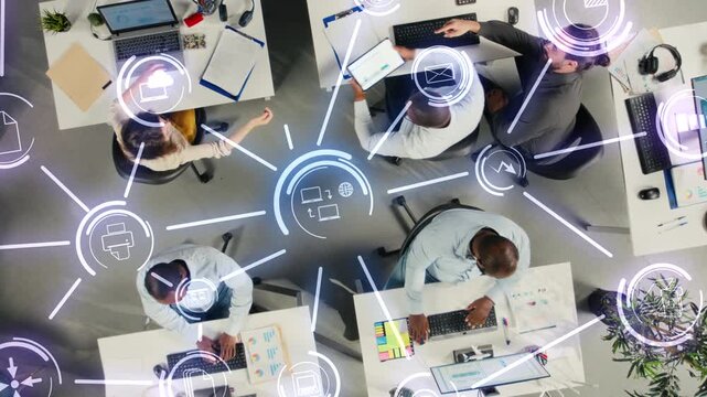 Collaborative team in company office sharing project files via cloud integration, digital ecosystem HUD icons. Aerial view of business colleagues syncing documents via online network on remote server