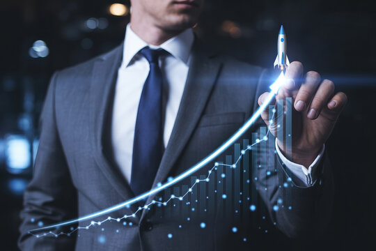 Businessman in gray suit touching a glowing rocket showing business growth and financial success - Powered by Adobe