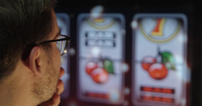 Back view of a person intensely watching a slot machine display, symbolizing gambling behavior, risk-taking, and signs of potential addiction.