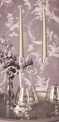 Old style retro candles and wine glass on a tray, vintage home decor on an a table, light tones