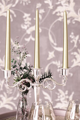 Old style retro candles and wine glass on a tray, vintage home decor on an a table, light tones