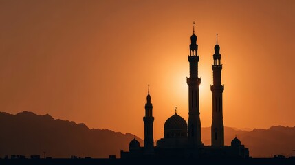 Silhouette of a Mosque Against a Sunset Sky with Mountainous Backdrop
