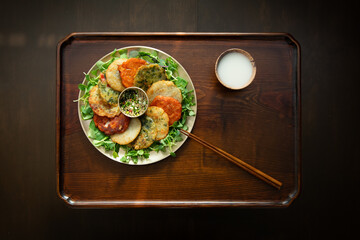 Assortment of Korean Jeon Pancakes with Makgeolli on a Wooden Tray