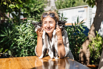 middle-aged woman holds a small black and white cat in her arms