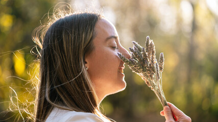 Woman smiling enjoying scent of lavender flowers