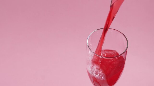 Bebida Espumosa Roja Verti&eacute;ndose en Copa sobre Fondo Rosa Minimalista con Espacio para Texto &ndash; Concepto Rom&aacute;ntico San Valent&iacute;n