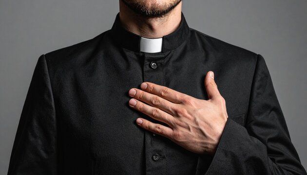 _Close up of priest with hand on chest wearing clerical collar and black suit for reli 777147.jpg