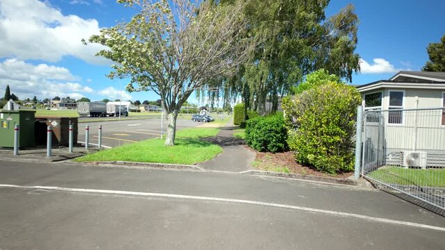 Suburban footpath with trees and rubbish bins on sunny day