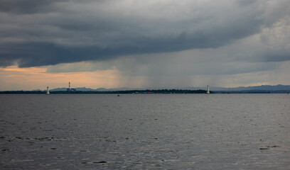 Rain Shower Falling Over the Ocean with Distant Lighthouse and Stormy Sky