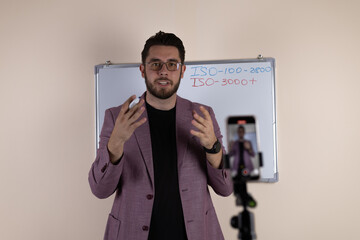 Male tutor or vlogger explaining material on a whiteboard in a studio