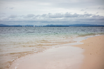 Fototapeta premium Tranquil Coastal Scene of Sand and Ocean Under Overcast Tropical Sky