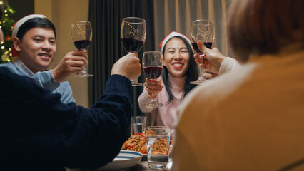 Group of Asia colleague friends gathering New year holidays party together. Happy man host toast glass of wine with guest start eat christmas dinner at home in evening, celebration and people concept.