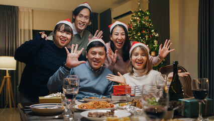 Group of Asia colleague gathering New year holidays party together. Happy friend look at camera video call online conference christmas thanksgiving dinner at home, celebrate and people concept.