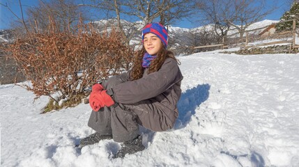 Child enjoys winter fun sliding headfirst on a sled in the snow on a sunny day in a snowy landscape