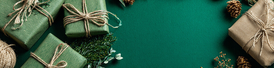 Christmas gifts wrapped in craft paper and string are arranged on a green background, perfect for a festive holiday season