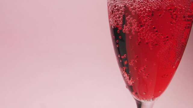 Plano cerrado de Bebida Espumosa Roja Verti&eacute;ndose en Copa con Burbujas sobre Fondo Rosa Minimalista &ndash; Concepto Rom&aacute;ntico San Valent&iacute;n.  C&aacute;mara lenta de una bebida ideal para texto y publicidad