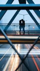 A couple shares a romantic moment on a bridge, silhouetted against a backdrop of city lights and traffic below. Perfect for urban romance or love stories.