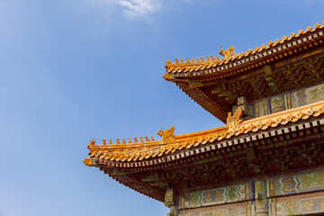 Fototapeta premium Sunlit golden roof with ornate ridge figures and vivid painted beams provides clear view of traditional Chinese imperial architecture in Forbidden City, Beijing, China