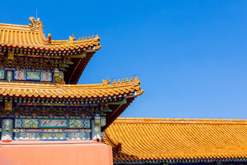 Warm ceramic tiles and carved decorative elements create strong contrast with bright blue sky...