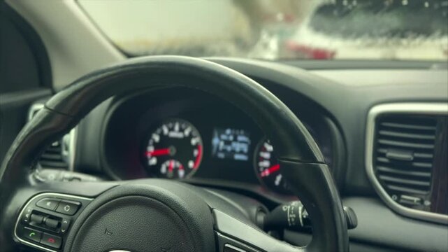 Heavy rain pounds against the windshield as the driver grips the steering wheel, creating a blurred